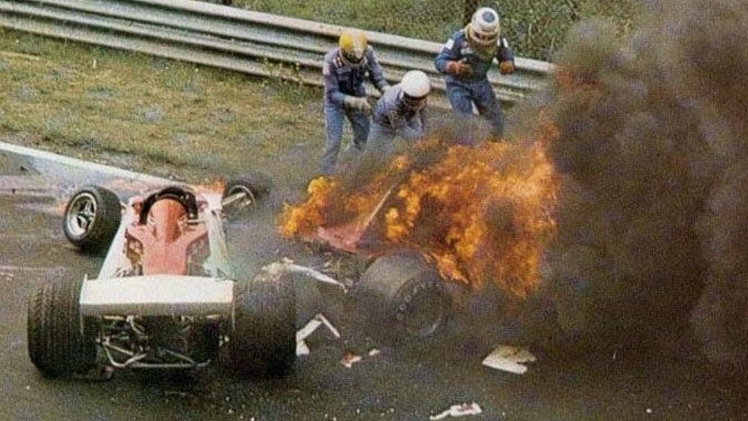 A destra, avvolta dalle fiamme, la carcassa dentro la quale Niki Lauda giace impotente.